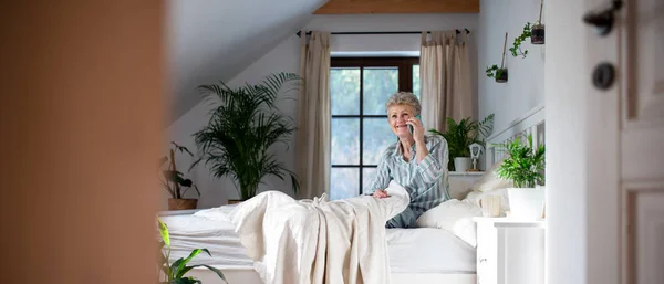 Glückliche Seniorin nutzt Smartphone zu Hause im Bett. — Stockfoto