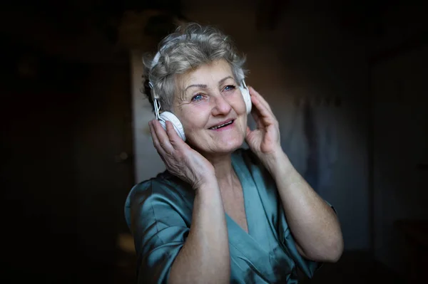 Glückliche Seniorin mit Kopfhörern, die zu Hause Musik hört, Entspannungs- und Selbsthilfekonzept. — Stockfoto