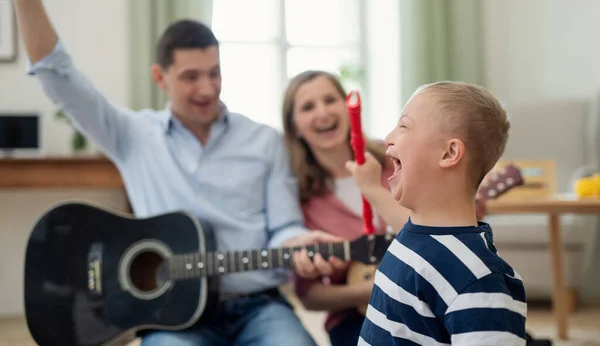 Fröhlicher Junge mit Down-Syndrom und Eltern, die Musikinstrumente spielen und lachen. — Stockfoto