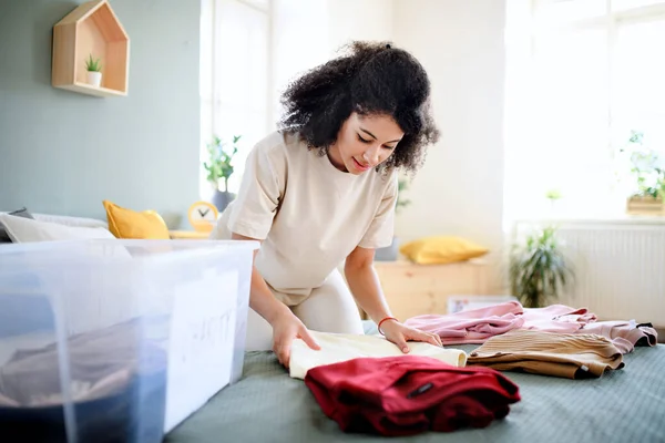 Mujer joven clasificando vestuario en el interior de casa, concepto de donación de caridad. —  Fotos de Stock