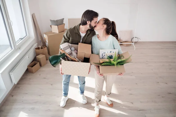 Jeune couple avec des boîtes s'embrassant lors du déménagement dans un nouvel appartement, nouvelle maison et concept de relocalisation. — Photo