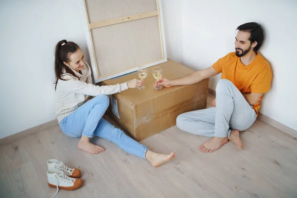 Jong echtpaar met dozen en wijn verhuizen in nieuwe flat, nieuw huis en verhuizing concept. — Stockfoto