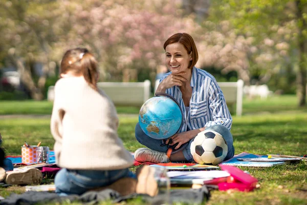 Lehrer mit kleinen Kindern sitzen draußen im Stadtpark, Lerngruppenpädagogik. — Stockfoto