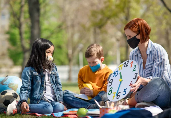 Leraar met kleine kinderen zit buiten in stadspark, leergroep onderwijs concept. — Stockfoto