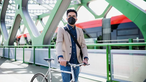 Молодой бизнесмен пригородный с велосипедом собирается работать на открытом воздухе на мосту в городе, коронавирусная концепция. — стоковое фото