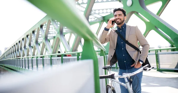 Joven hombre de negocios viajero con bicicleta que va a trabajar al aire libre en la ciudad, utilizando el teléfono inteligente. — Foto de Stock