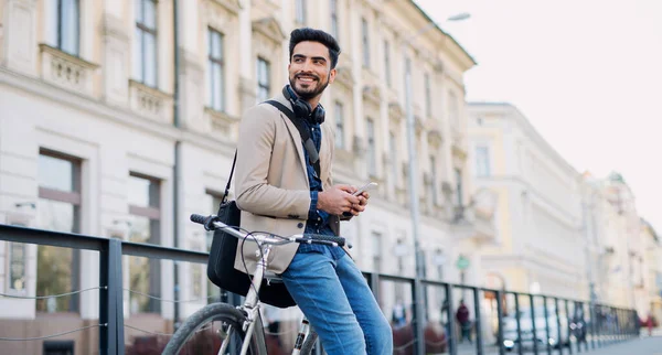 Joven hombre de negocios viajero con bicicleta que va a trabajar al aire libre en la ciudad, utilizando el teléfono inteligente. — Foto de Stock