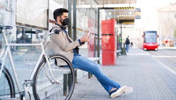 Joven hombre de negocios viajero con teléfono inteligente en el camino al trabajo al aire libre en la ciudad, coronavirus concepto. — Foto de Stock