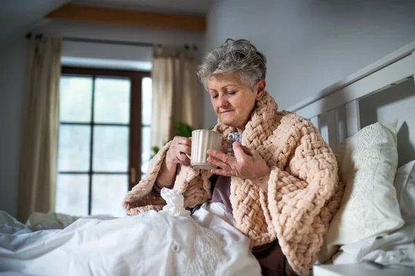 Sick senior woman in bed at home, taking medication. Post-vaccination side-effects. — Stock Photo, Image