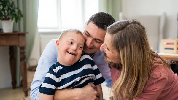 Fröhlicher Junge mit Down-Syndrom und Eltern zu Hause beim Umarmen. — Stockfoto