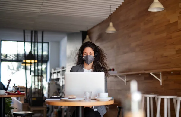 Бизнесвумен с ноутбуком, работающая в кафе, фрилансером и коронавирусом. — стоковое фото