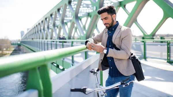 Joven hombre de negocios viajero con bicicleta que va a trabajar al aire libre en la ciudad, utilizando el teléfono inteligente. — Foto de Stock