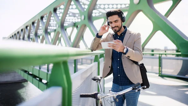 Joven hombre de negocios viajero con bicicleta va a trabajar al aire libre en la ciudad, videollamada en el teléfono inteligente. — Foto de Stock
