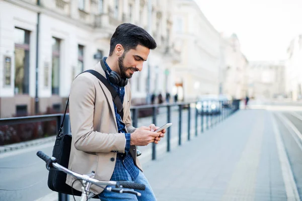 Bisikletli genç bir iş adamı şehir dışında çalışıyor, akıllı telefon kullanıyor.. — Stok fotoğraf