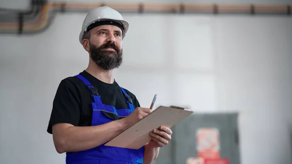 Vista de bajo ángulo del trabajador con casco interior en portapapeles de fábrica. — Foto de Stock