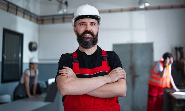 Ritratto di lavoratore con casco all'interno in fabbrica guardando la macchina fotografica. — Foto Stock