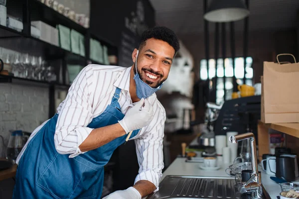 Πορτρέτο του σερβιτόρου κοιτάζοντας κάμερα σε καφέ, μικρές επιχειρήσεις, coronavirus και νέα κανονική έννοια. — Φωτογραφία Αρχείου