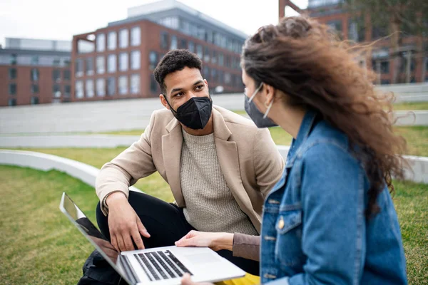 Homem e mulher com laptop trabalhando ao ar livre no parque na cidade, conceito coronavírus. — Fotografia de Stock