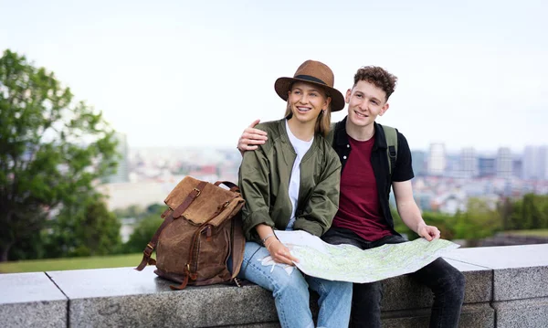 Young couple travelers with map in city on holiday, resting and planning. — Stock Photo, Image