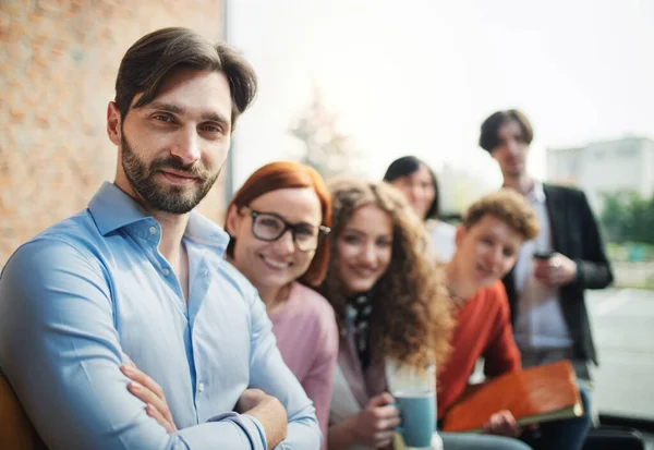 Portret van jonge zakenman met groep ondernemers binnen in kantoor, kijkend naar camera. — Stockfoto