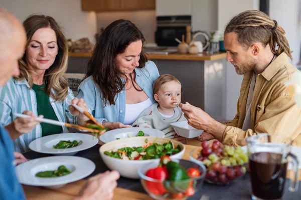 Счастливая семья, состоящая из нескольких поколений, дома ест здоровый обед. — стоковое фото