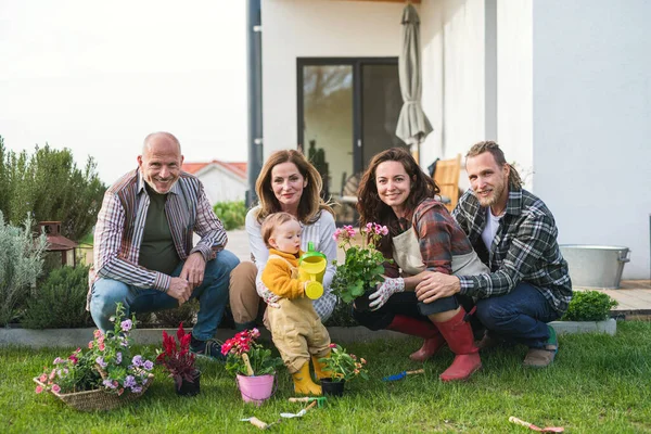 Szczęśliwa wielopokoleniowa rodzina na zewnątrz sadzenie kwiatów w ogrodzie w domu, koncepcja ogrodnictwa. — Zdjęcie stockowe