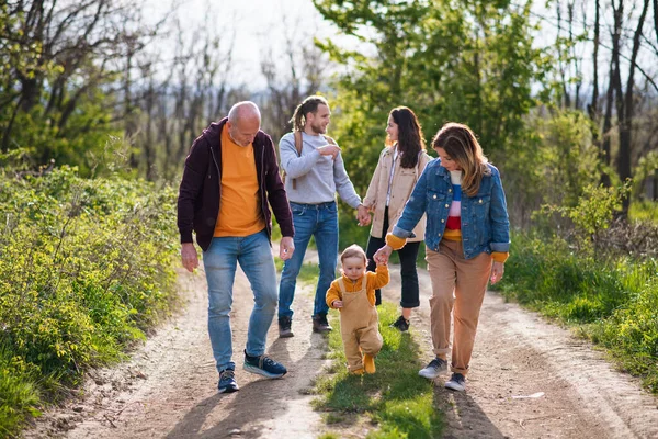 Small toddler with parents and grandparents on a walk outdoors in nature. — Stock Photo, Image