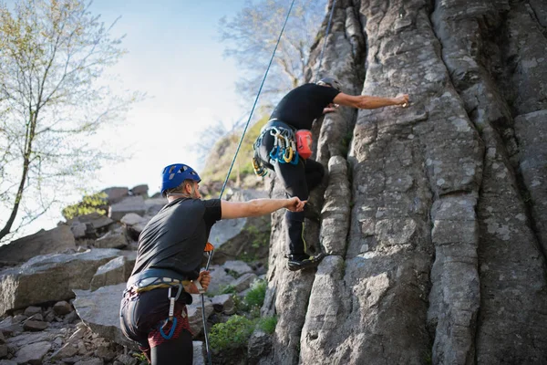 Senior man med instruktör klättra stenar utomhus i naturen, aktiv livsstil. — Stockfoto