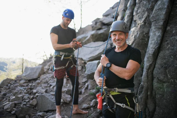 Senior man med instruktör klättra stenar utomhus i naturen, aktiv livsstil. — Stockfoto