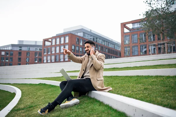 Uomo con laptop e smartphone all'aperto nel parco in città, al lavoro. — Foto Stock