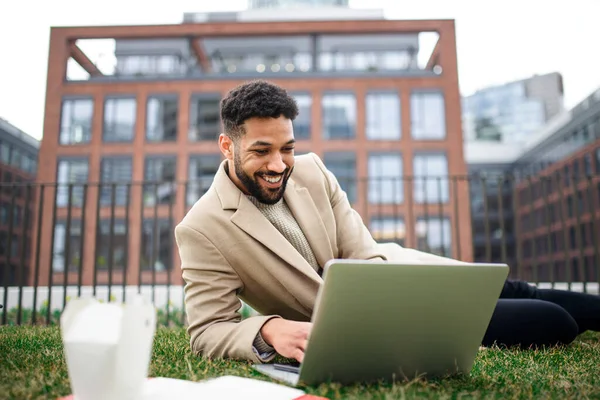 Man met laptop werkt buiten in park in stad, remote office concept. — Stockfoto