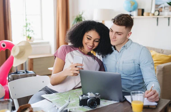 Pareja joven con computadora portátil y embalaje de teléfonos inteligentes para las vacaciones, tomando selfie. — Foto de Stock