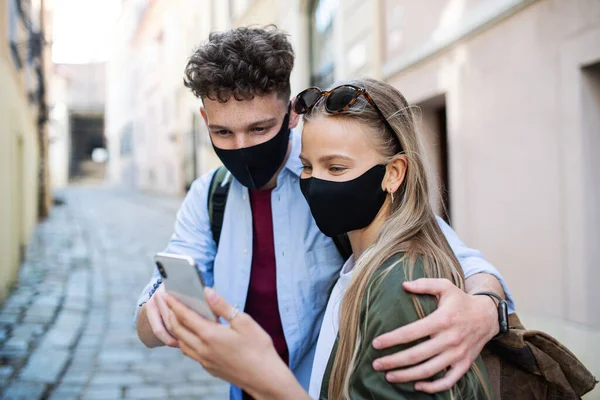 Jovens viajantes casal usando smartphones sightseeing na cidade de férias, conceito coronavirus. — Fotografia de Stock