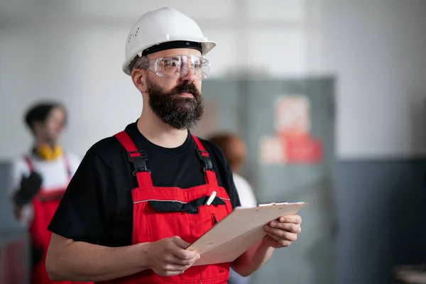 Портрет работника со шлемом и защитными очками в помещении завода с планшетом. — стоковое фото