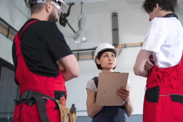 Группа работников со шлемом в помещении на заводе, обсуждают вопросы. — стоковое фото