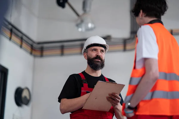 Portret van mannen werknemers met helm binnen in de fabriek, bespreken van kwesties. — Stockfoto