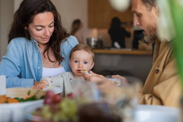 A boldog pár otthon ebédel az asztalnál, eteti a babát.. — Stock Fotó