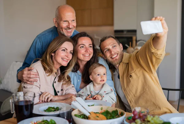 Família multigeracional feliz dentro de casa almoçando saudável, tomando selfie. — Fotografia de Stock