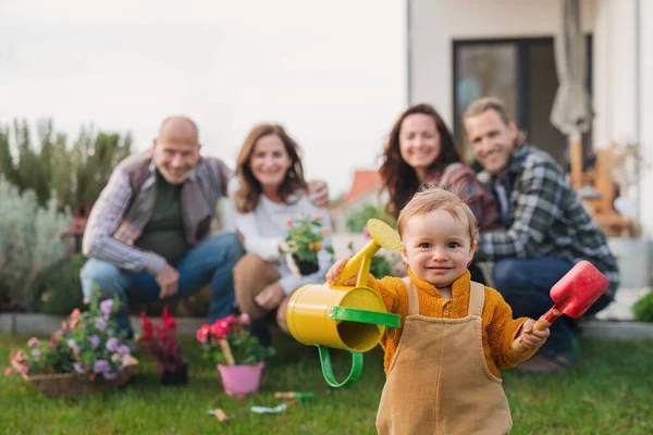Happy multigeneration family outdoors planting flowers in garden at home, gardening concept. — Stock Photo, Image