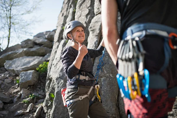 Femme âgée avec instructeur escalade rochers en plein air dans la nature, mode de vie actif. — Photo