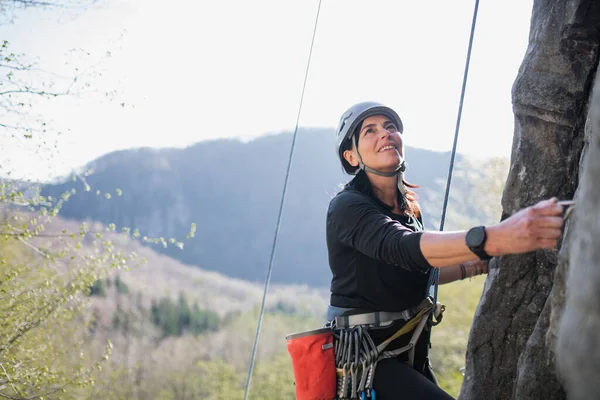 Femme âgée escalade rochers en plein air dans la nature, mode de vie actif. — Photo