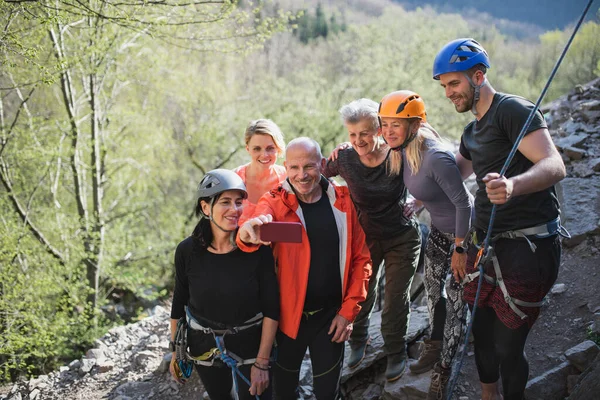 Seniorengruppe mit Instruktor macht Selfie nach dem Klettern an Felsen in der Natur, aktiver Lebensstil. — Stockfoto