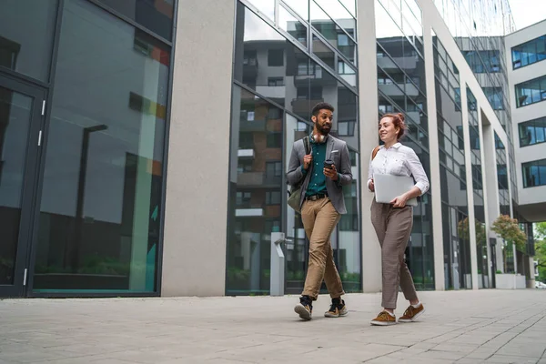 Studenter går framför byggnaden utomhus i staden, pratar. — Stockfoto