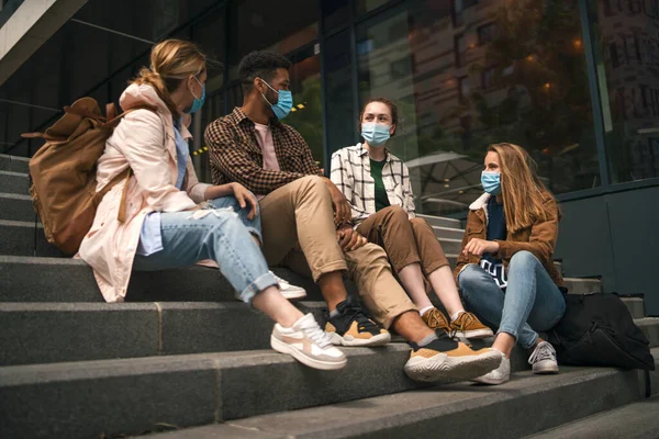 Grupo de amigos estudantes ao ar livre sentado e falando na cidade, coronavírus e de volta ao conceito normal. — Fotografia de Stock