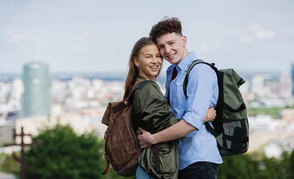 Jóvenes viajeros en pareja en la ciudad de vacaciones, mirando a la cámara. Paisaje urbano en el fondo. — Foto de Stock