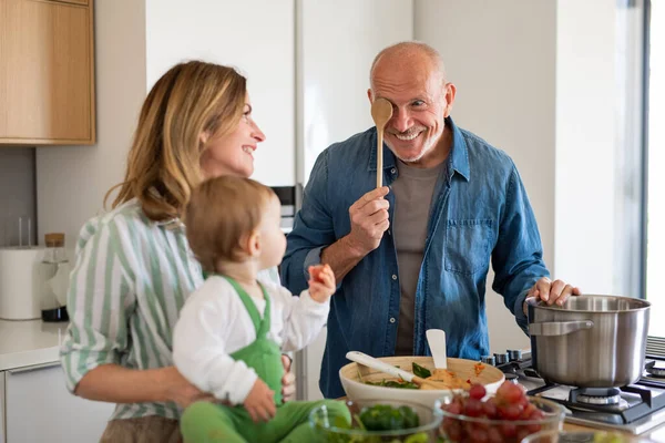 Senior par med barnbarn inomhus, matlagning. — Stockfoto