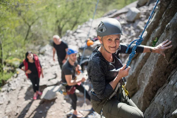 Grupp av seniorer med instruktör klättra stenar utomhus i naturen, aktiv livsstil. — Stockfoto