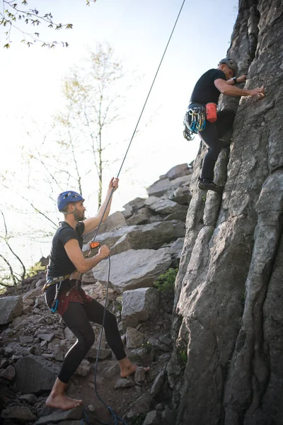 Senior homme avec instructeur escalade rochers en plein air dans la nature, mode de vie actif. — Photo