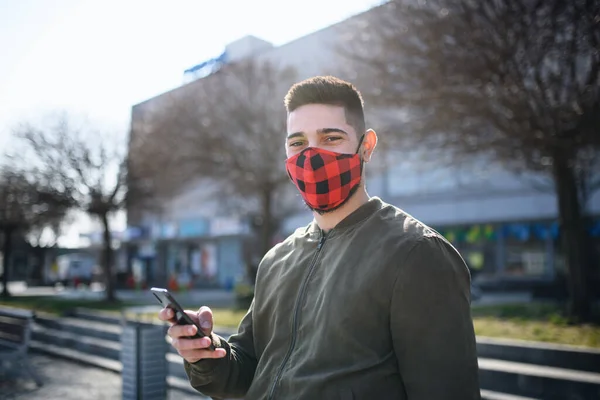 Молодой человек на улице в городе с помощью смартфона, коронавируса и новой нормальной концепции. — стоковое фото