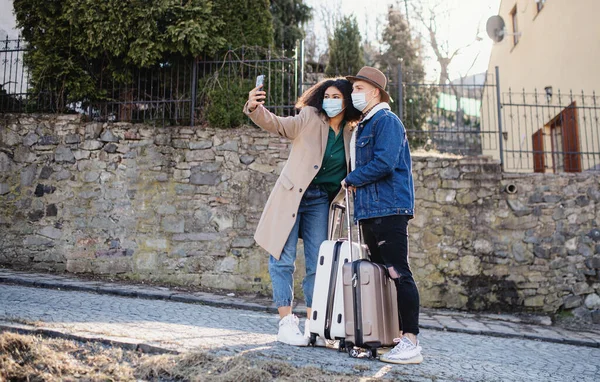 Joven pareja de turistas con equipaje tomando selfie en la calle en el casco antiguo, coronavirus concepto. — Foto de Stock